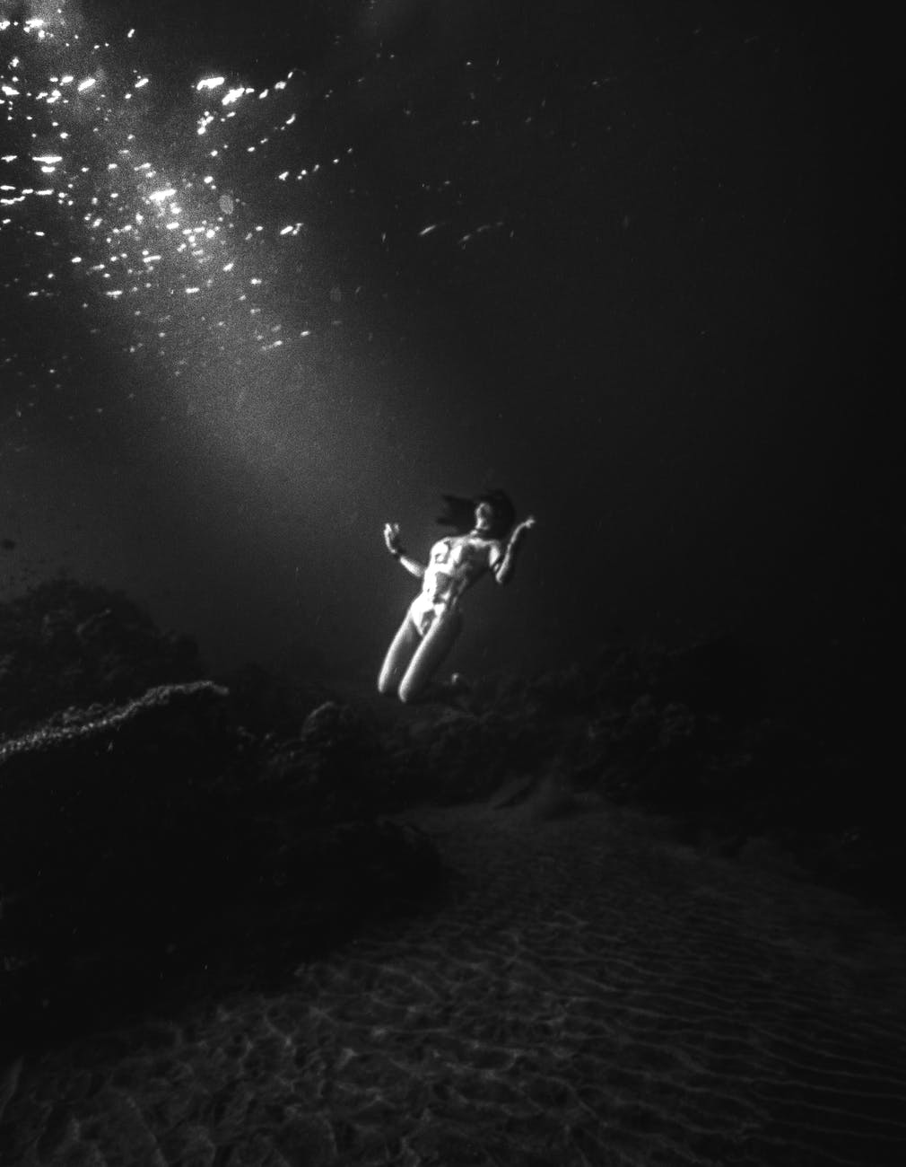 grayscale photo of woman swimming underwater