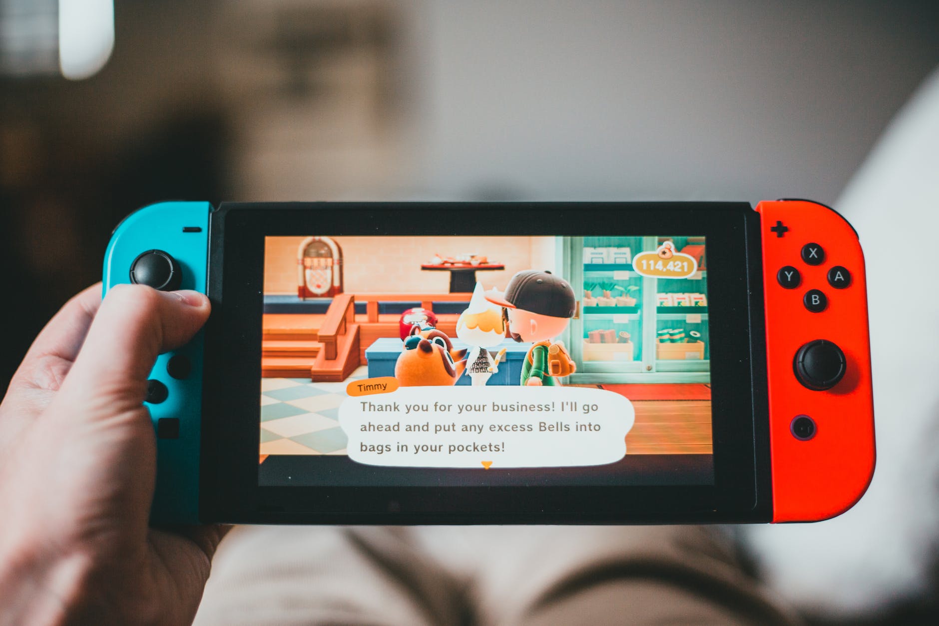 Crop of person using Nintendo Switch game console. It has characters on the screen in a conversation.