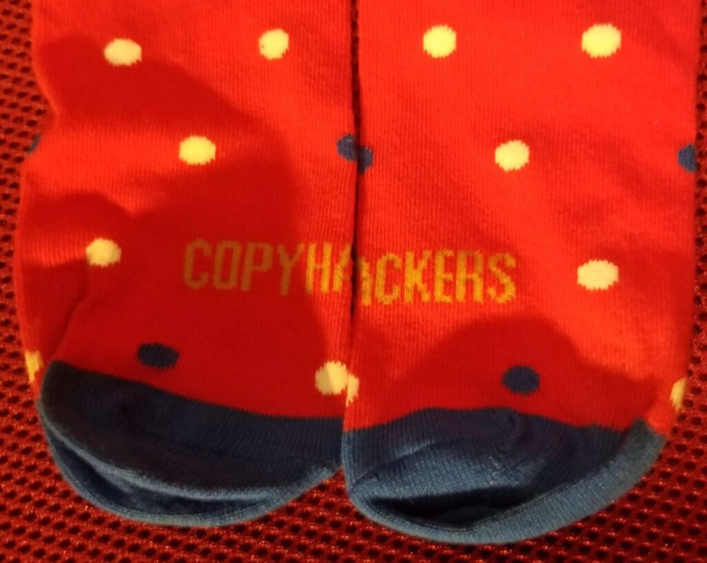 Pair of Copyhackers socks on red chair background.